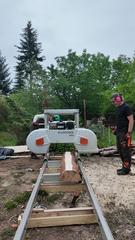 Mobil szalagfűrész munka közben, felfűrészelt rönkkel